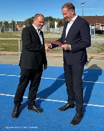 Der Parlamentarische Staatssekretär für Vorpommern und das östliche Mecklenburg Heiko Miraß (r.) übergibt auf der Sport- und Trainingsanlage 